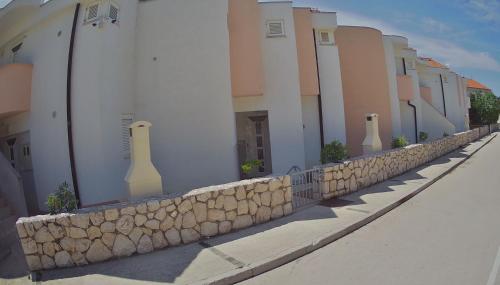 a stone retaining wall next to a building at Apartments Pag-Travel in Novalja