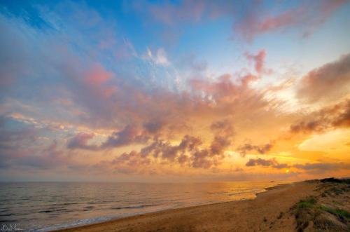 a sunset on the beach with a cloudy sky at Christinas lofts in Ágios Matthaíos