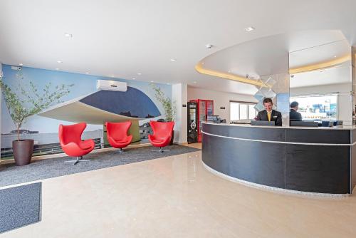 a lobby with red chairs and a reception desk at Slim Curitiba João Bettega in Curitiba