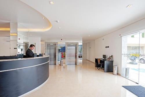 a man standing at a counter in a building at Slim Curitiba João Bettega in Curitiba