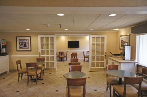 a waiting room with tables and chairs and a tv at La Quinta by Wyndham Tampa Fairgrounds - Casino in Tampa