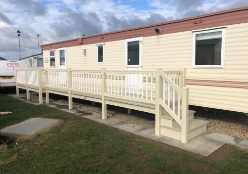 a mobile home with a porch and a white railing at ML66 8 BERTH CARAVAN GOLDEN PALM CHAPEL ST LEONARDS in Chapel Saint Leonards