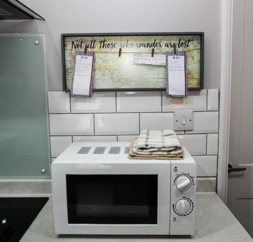 a microwave on a counter with a sign on a wall at No 4 New Inn Apartments in Newark upon Trent