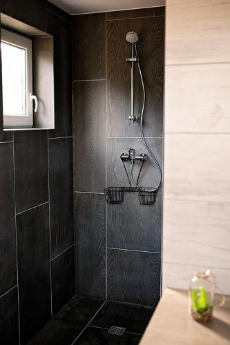 a bathroom with a shower with black tiles at Zakątek Nad Jeziorem in Łyśniewo