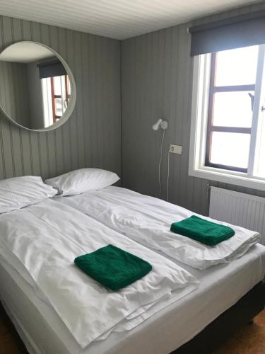 Una cama blanca con dos toallas verdes. en Sólbakki Holiday Home, en Egilsstadir