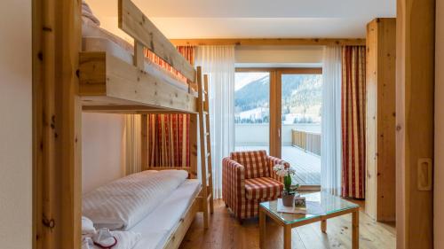 a hotel room with a bunk bed and a chair at Family Resort Rainer in Sesto