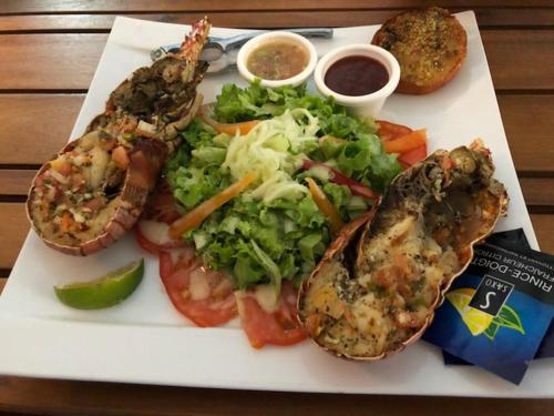 a plate of food with shrimp and salad and dipping sauce at Ste Anne Martinique Studio bord de mer Résidence Anse Caritan in Sainte-Anne