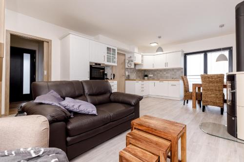 a living room with a brown couch and a kitchen at NESS by Mountain ways in Boží Dar