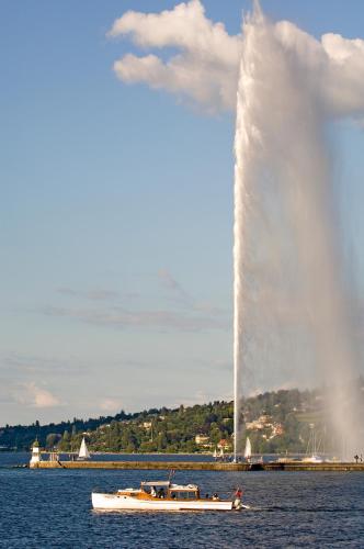 a white boat in the water with a large fountain at Novotel Genève Centre in Geneva