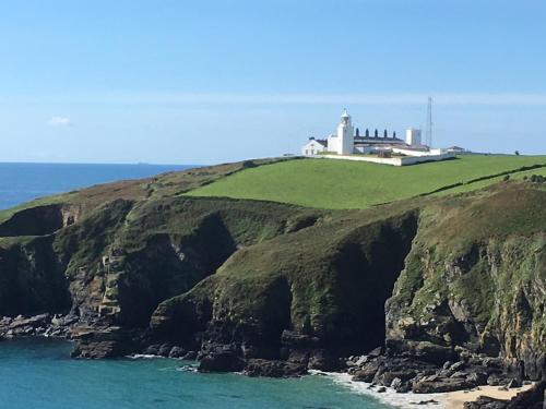 a lighthouse on top of a cliff near the ocean at Haelarcher Farmhouse and Helicopter B&B in Lizard