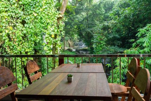 a wooden table and chairs on a balcony at Namtok Sarika Resotel in Nakhon Nayok