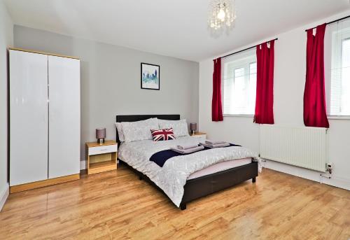 a bedroom with a bed and red curtains at Harlinger Lodge in London
