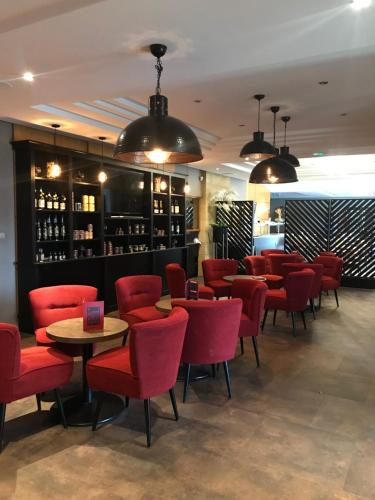 a restaurant with red chairs and a bar at Hôtel Grand Confort Le Moulin Rouge in Terrasson-Lavilledieu