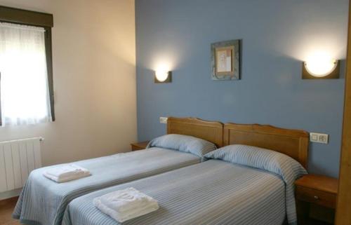 two beds in a bedroom with two towels on them at Apartamentos Rurales La Granda in Cangas de Onís