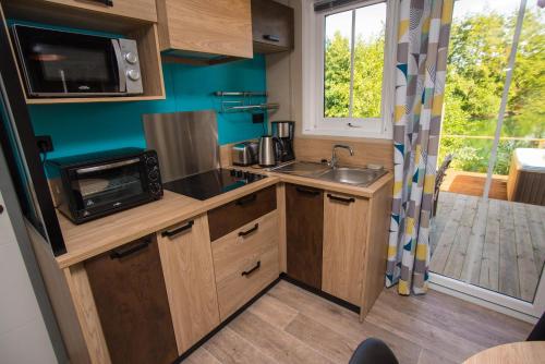 a small kitchen with a sink and a microwave at Camping du Château Vert in Hondainville