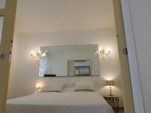 Schlafzimmer mit einem weißen Bett und einem Spiegel in der Unterkunft Lovely 1 Bedroom Boulevard de la Croisette in Cannes