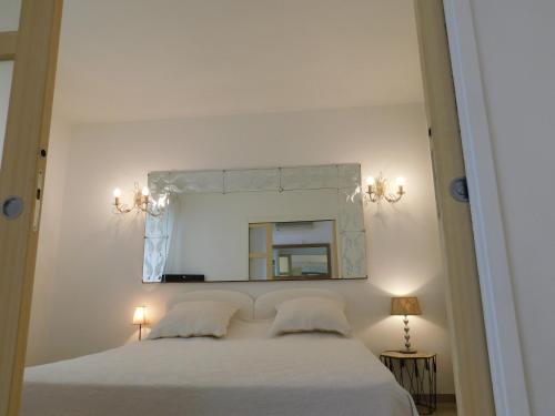 une chambre avec un lit blanc et un miroir dans l'établissement Lovely 1 Bedroom Boulevard de la Croisette, à Cannes