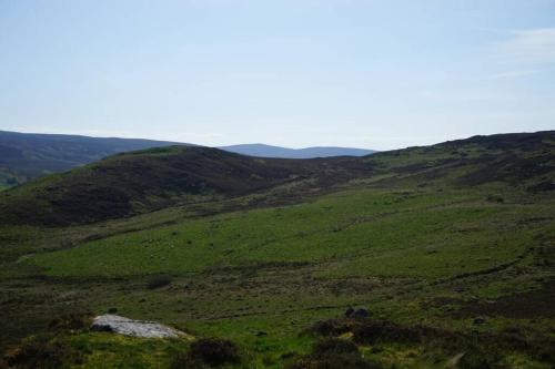 a green field with hills in the background at Burnside Cottage on the Blarich Estate in Rogart