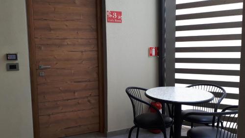 a table and chairs in a room with a door at Hotel Bed & Rooms , Corte Rossa -1 Min Walk To Bernina Express in Tirano