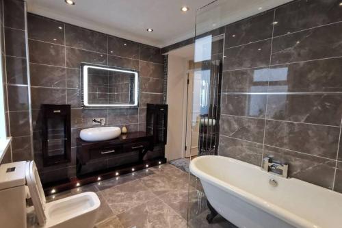 a bathroom with a bath tub and a sink at Broomfield Cottage South Luss in Glasgow
