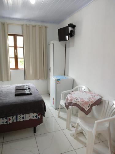 a bedroom with a bed and a table and chairs at Residencial Dona Duda in Bombinhas
