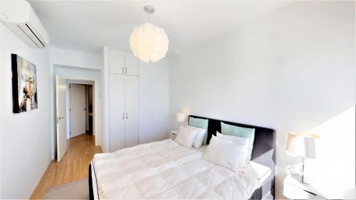 - une chambre avec un grand lit blanc et un lustre dans l'établissement Olimpo - Fuengirola Beachfront Newly Renovated Apartment, à Fuengirola
