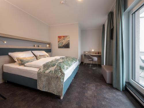 a bedroom with a bed and a desk and a window at RS-HOTEL - smart & modern Hotel Apartments in Brühl