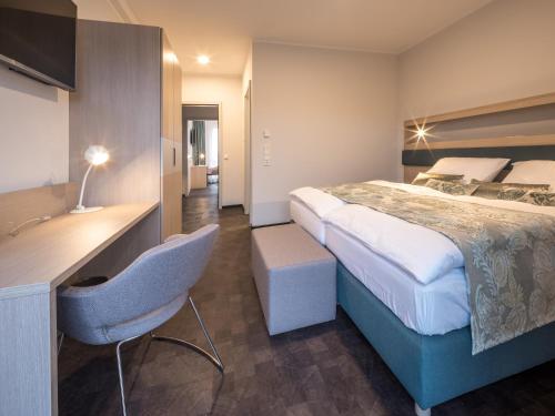ein Hotelzimmer mit einem großen Bett und einem Schreibtisch in der Unterkunft RS-HOTEL - smart & modern Hotel Apartments in Brühl