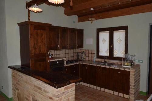 uma cozinha com armários de madeira e uma parede de tijolos em Villa Manu em Lapedona