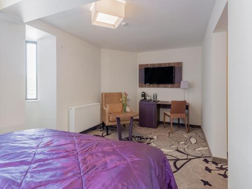 a bedroom with a bed and a table and a tv at Hotel Miruna - New Belvedere in Poiana Brasov