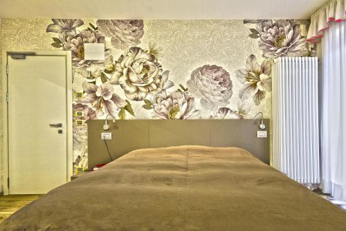 1 dormitorio con 1 cama y papel pintado con motivos florales en Hotel Venezia, en Rocca Pietore