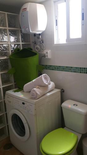 uma lavandaria com uma máquina de lavar roupa e um banco verde em finca Lotusflower em Aguatona
