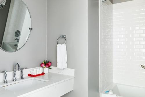 Baño blanco con lavabo y espejo en White Swan Inn en San Francisco