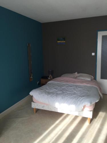 a bedroom with a bed with a blue wall at Chez Mimi in Châtillon-sur-Seine