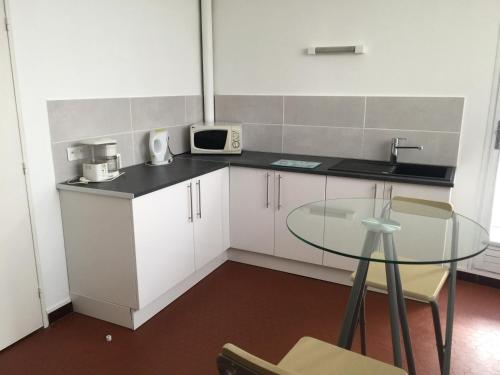 a small kitchen with a glass table and a microwave at Chez Mimi in Châtillon-sur-Seine