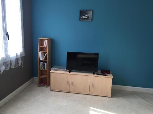 - une télévision assise sur une table dans une pièce dotée d'un mur bleu dans l'établissement Chez Mimi, à Châtillon-sur-Seine