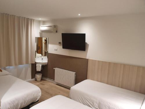 a hotel room with two beds and a flat screen tv at Hostal BESTPRICE Barcelona Stadium in Barcelona