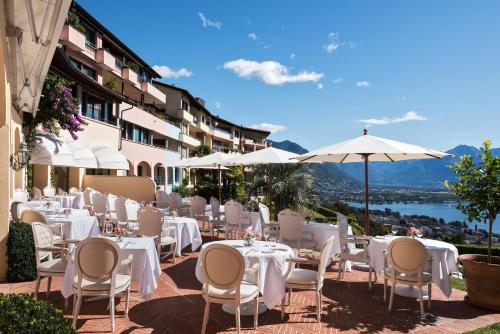 a patio area with tables and chairs and umbrellas at Villa Orselina - Small Luxury Hotel in Locarno