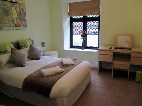 a bedroom with a bed and a desk and a window at Queens Head Inn in Monmouth