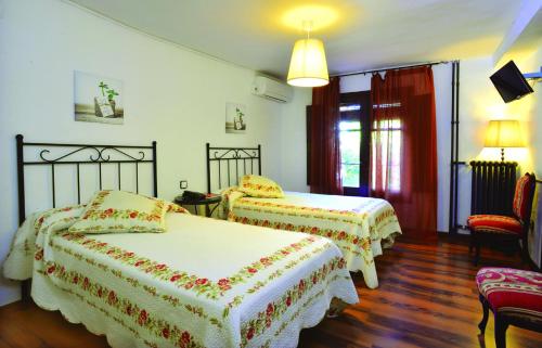 a hotel room with two beds and a chair at Hotel Rio Piedra in Nuévalos
