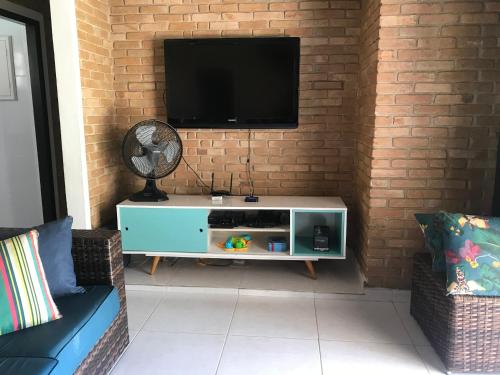 uma sala de estar com televisão numa parede de tijolos em Ampla casa com piscina a 200 metros da praia do Lazaro e Sununga em Ubatuba