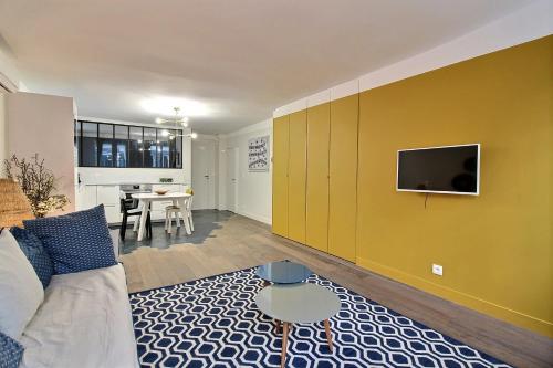 a living room with a couch and a tv on a wall at 102216 - Appartement 4 personnes Montorgueil in Paris