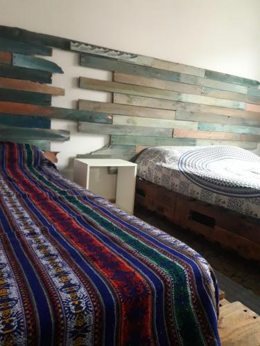 a bedroom with two beds and a wooden wall at Casa Indaiá BnB - casa compartilhada in Caraguatatuba
