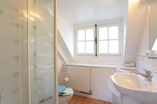 baño con lavabo y aseo y ventana en Restaurant & Chambres d'Hôtes L'Eau Vive, en Fatouville-Grestain