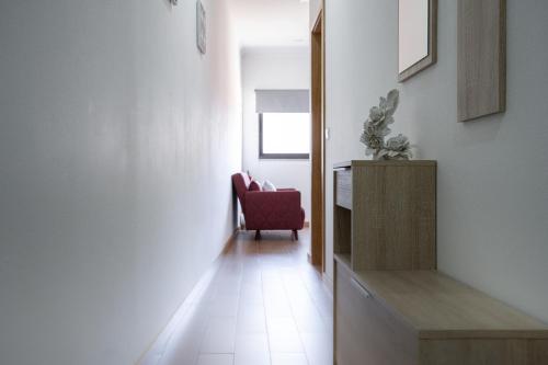 a hallway with a red chair in a room at D'OURO DOM MANUEL By LW in Vila Nova de Gaia