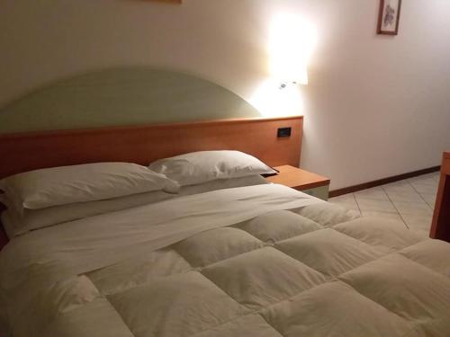 a large white bed in a room with a lamp at Hotel Il Cammino Di Francesco in Bastia Umbra