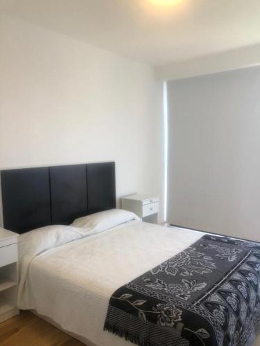 a bedroom with a bed with a black and white blanket on it at Departamento de 2 ambientes luminoso in Mar del Plata
