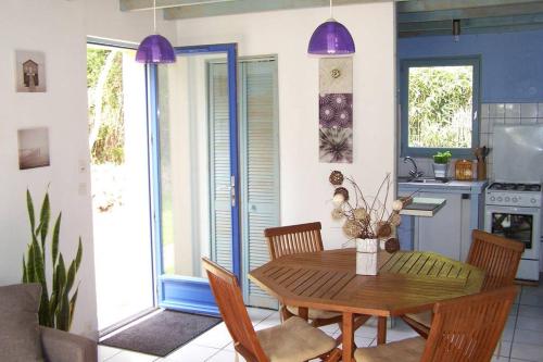 Il dispose d'une cuisine avec une table en bois, des chaises et des lumières violettes. dans l'établissement Maison avec jardin clos. Animaux acceptés - Wifi - Proche plages de la Trinité sur Mer et Carnac, à La Trinité-sur-Mer