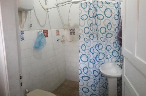 a bathroom with a shower curtain and a sink at Casa Indaiá BnB - casa compartilhada in Caraguatatuba