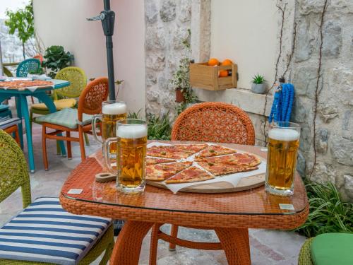 a table with a pizza and two glasses of beer at Apartments Windrose in Kotor